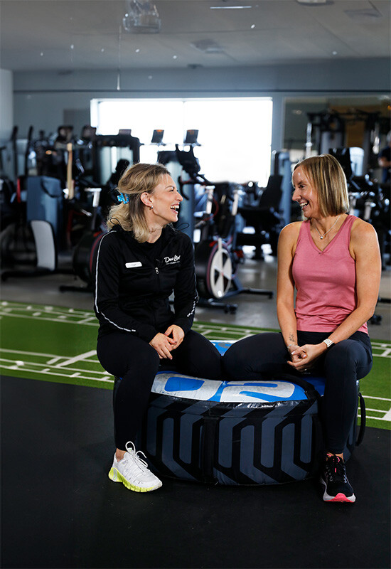 A woman chats with her personal trainer in the gym