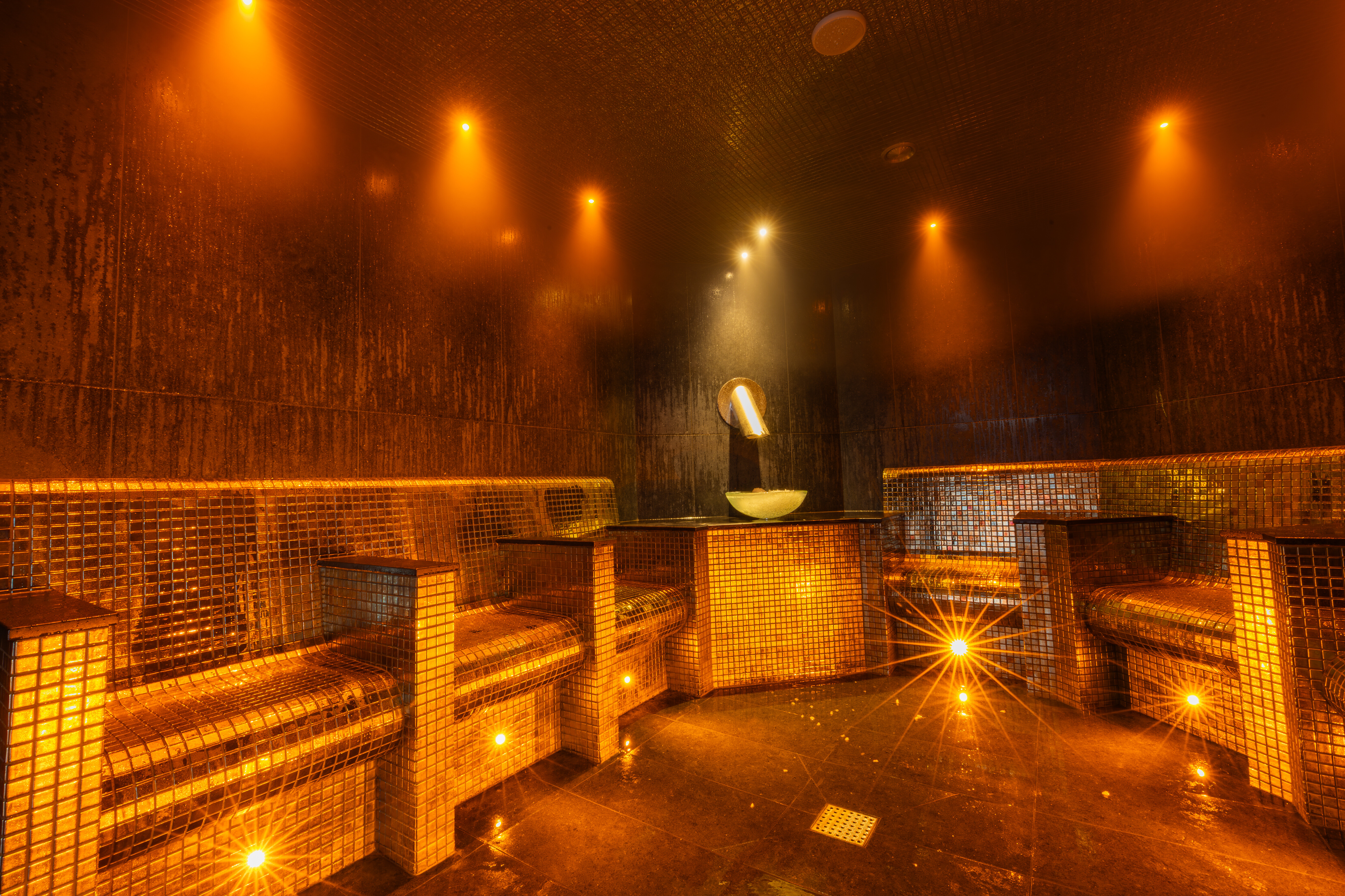 Warm amber lights glowing with tiled seats and a bowl of ice in the corner of the fire and ice room