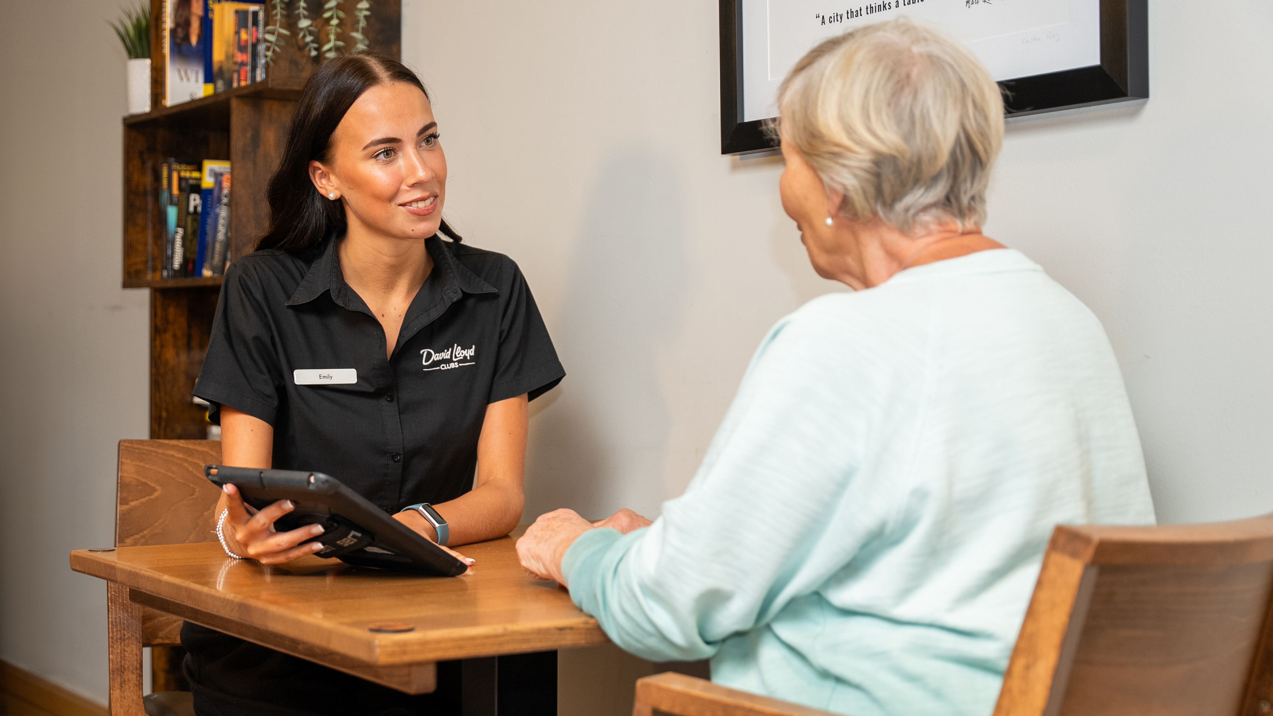 A team member holds a tablet, demonstrating how it works to a member 