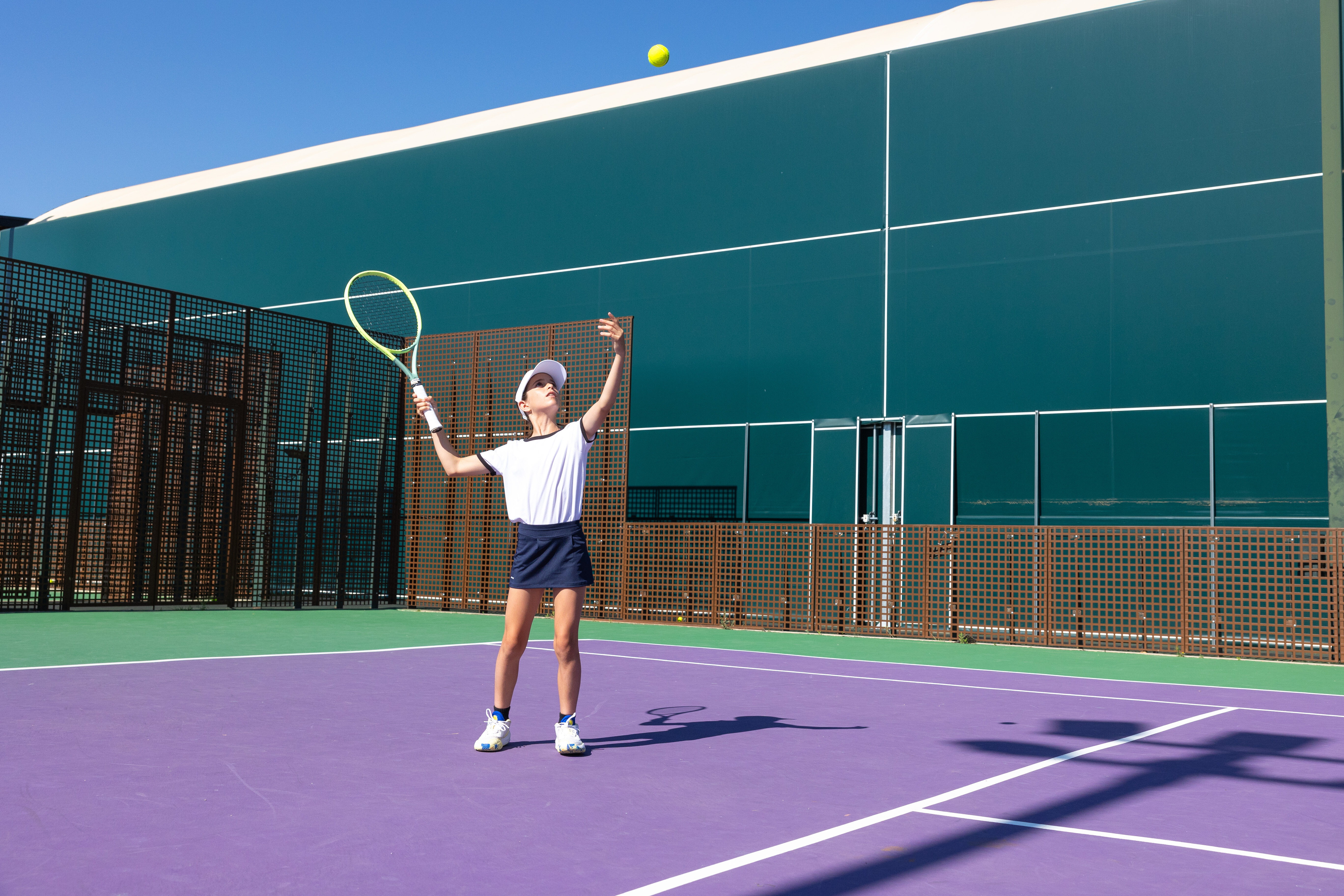 A teenage girl serves with the ball in the air