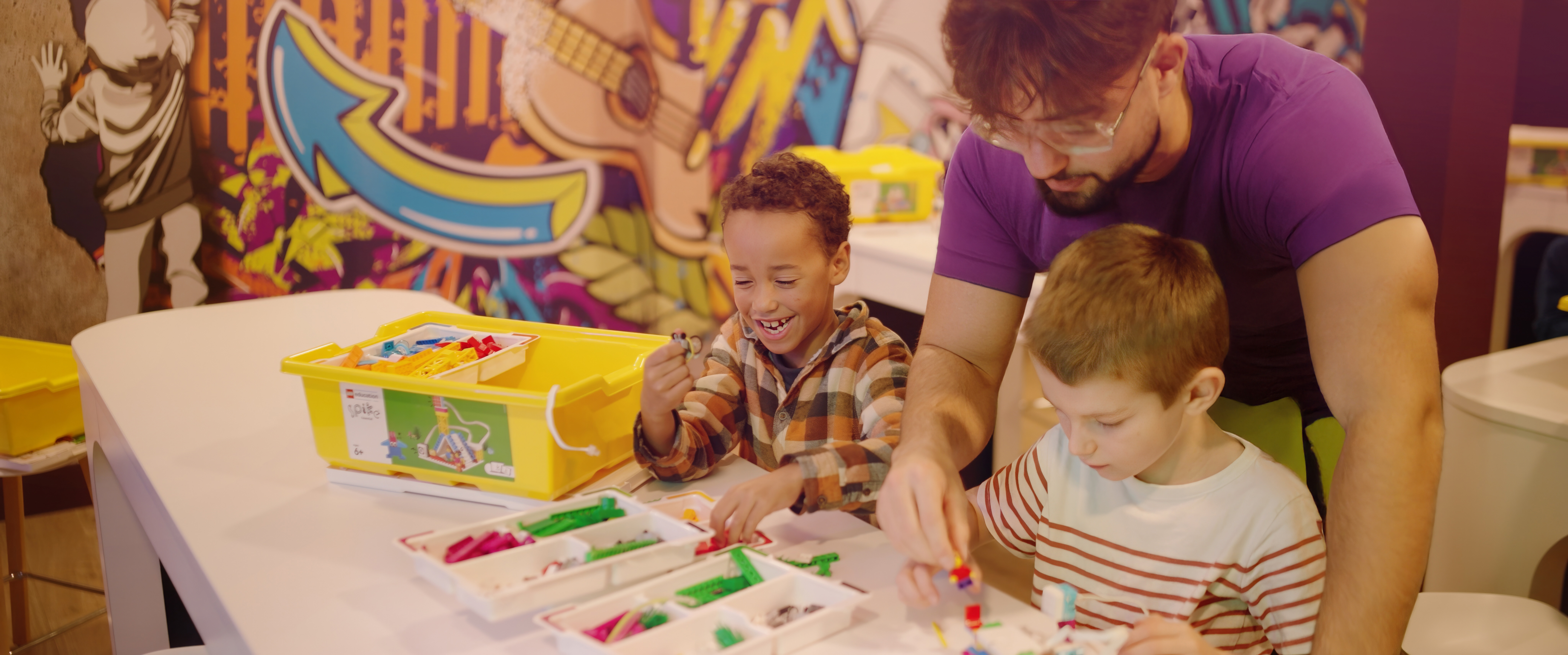 A DL Kids team member helps two young children