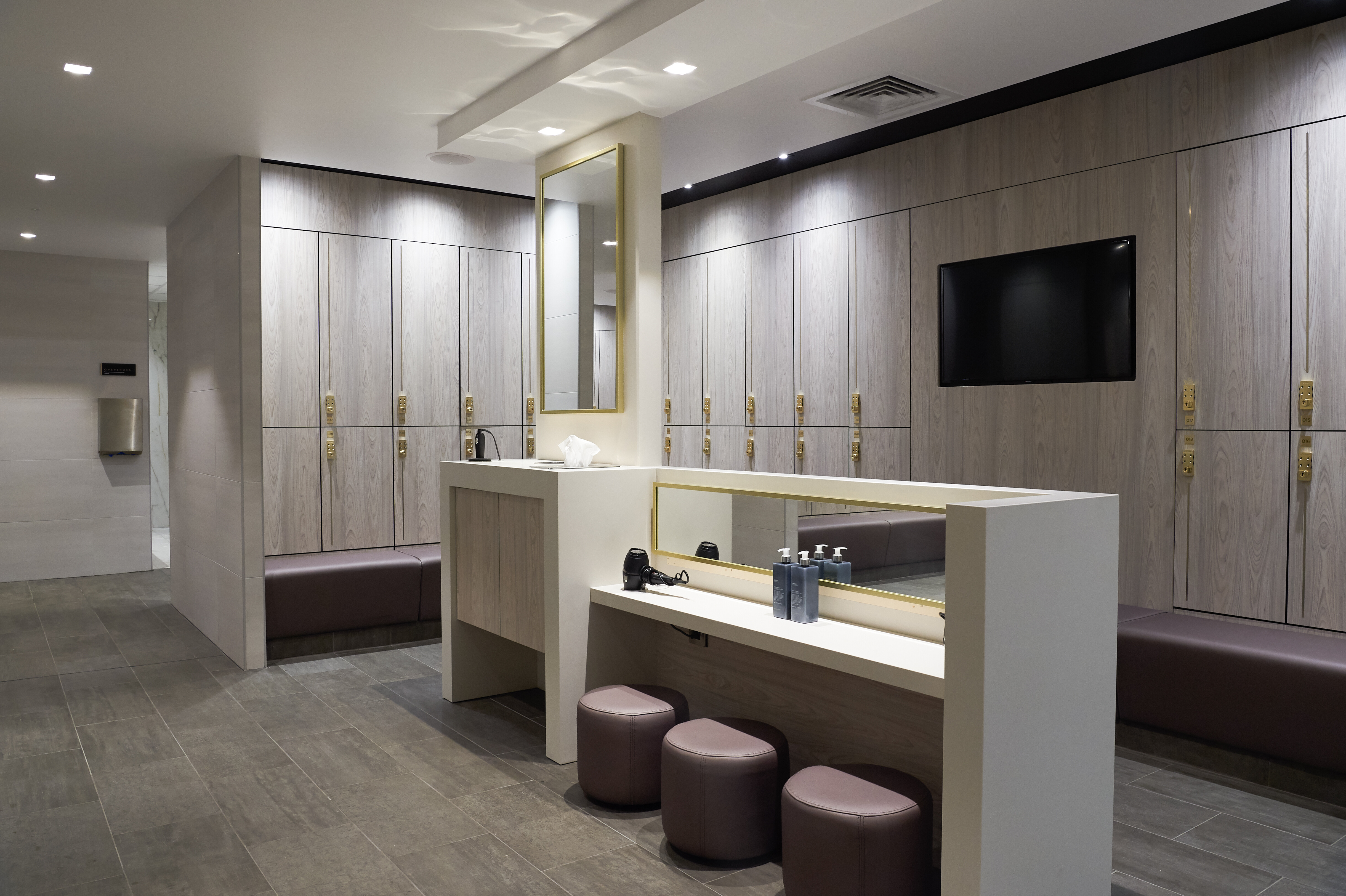 Changing room with lockers and stools to sit in front of a mirror with hairdryers