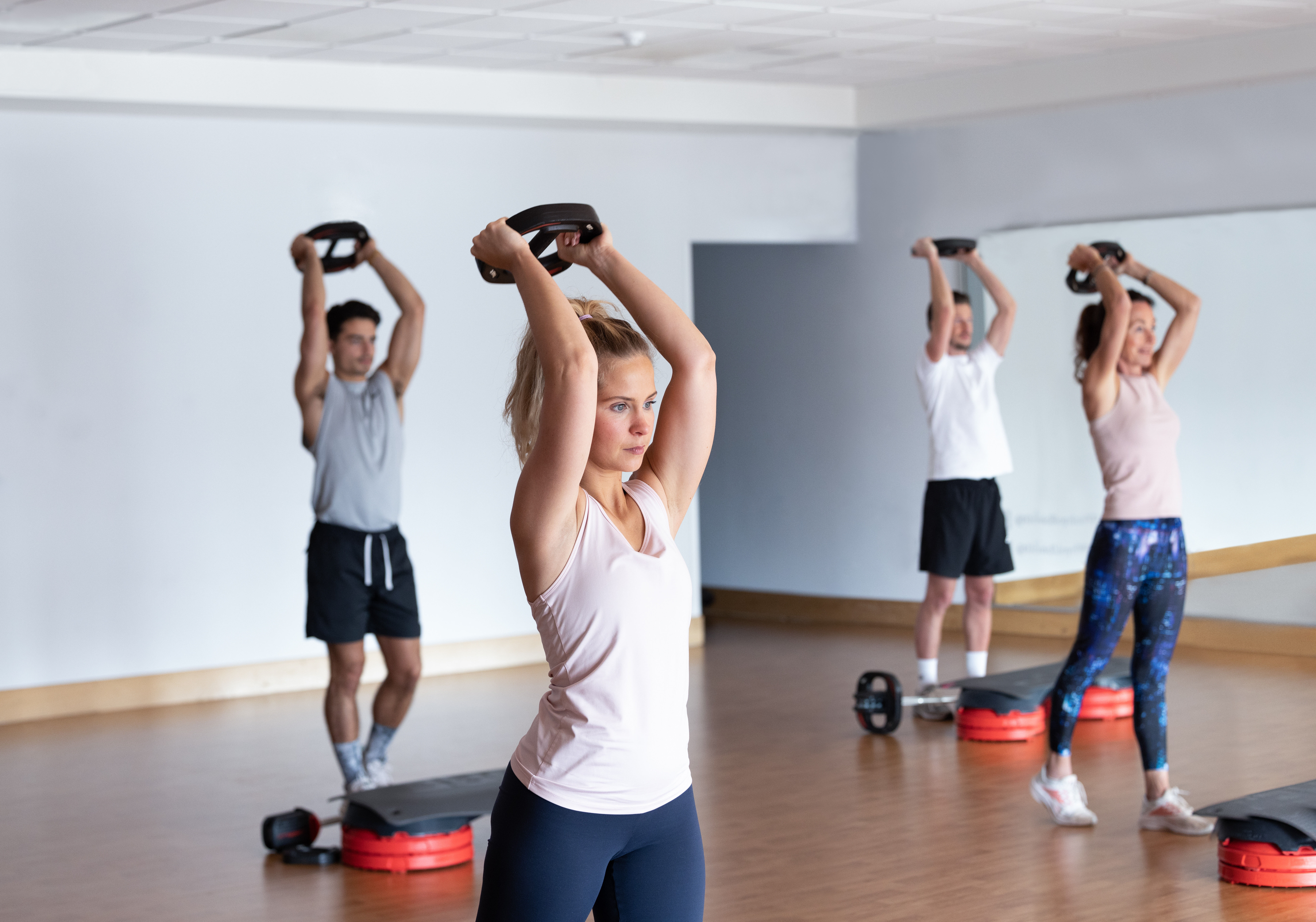 A group class holds weights above their heads