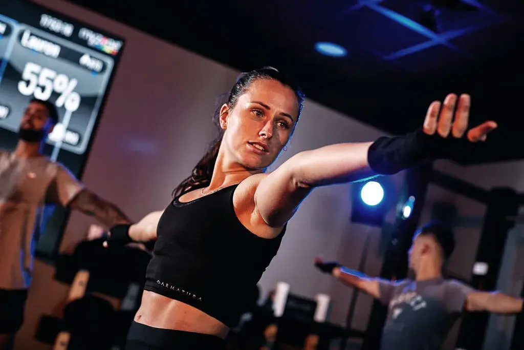 Woman wearing a MYZONE belt with stats on the screen in the background