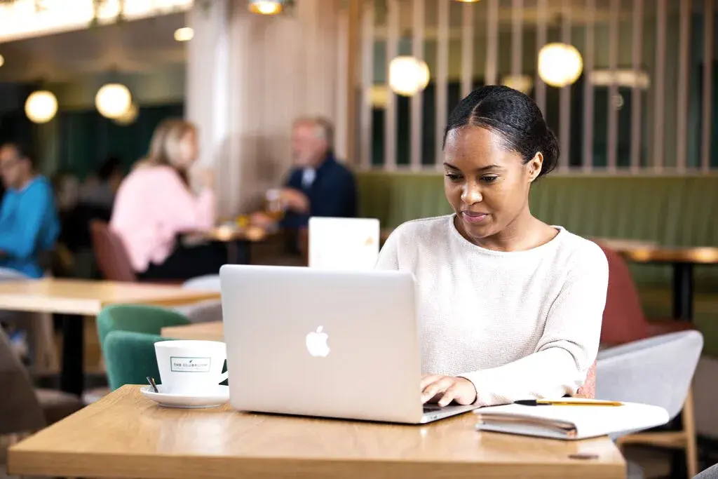 A woman working on a laptop in the clubroom of a david lloyd club.