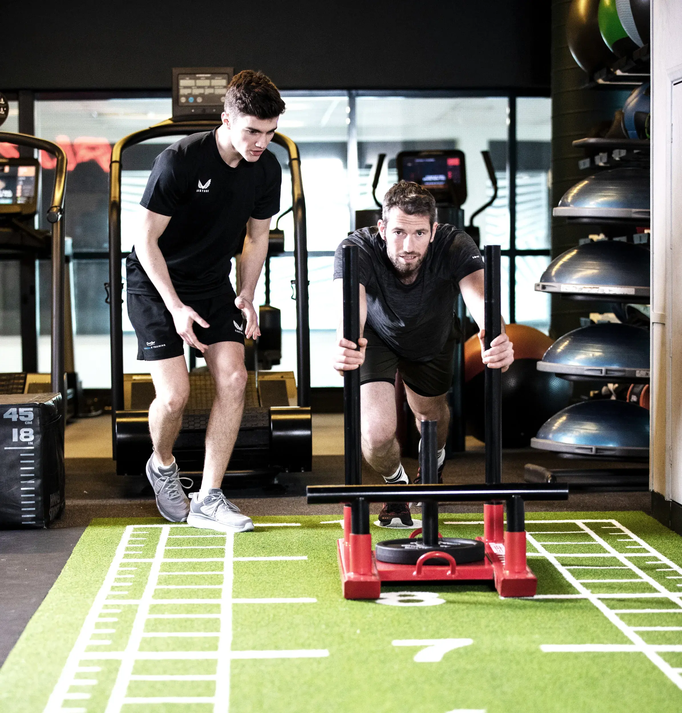 Man pushing weights with personal trainer