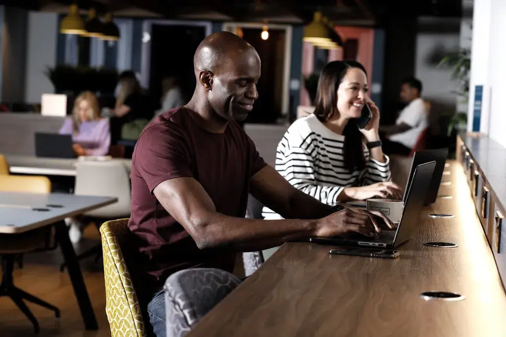 Two people working on laptops in a David Lloyd Clubs workstation.