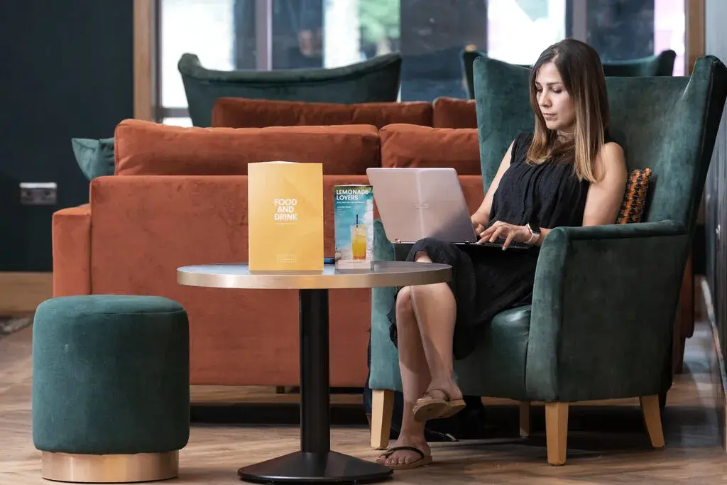 A woman working on a laptop in a david lloyd clubs clubroom.