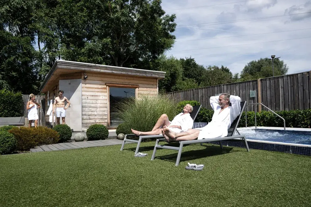 People relaxing on loungers in a David Lloyd Clubs spa garden.