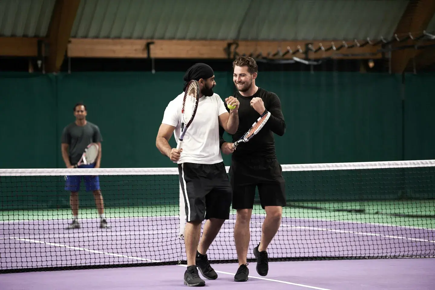 Two men playing tennis on a David Lloyd indoor tennis court