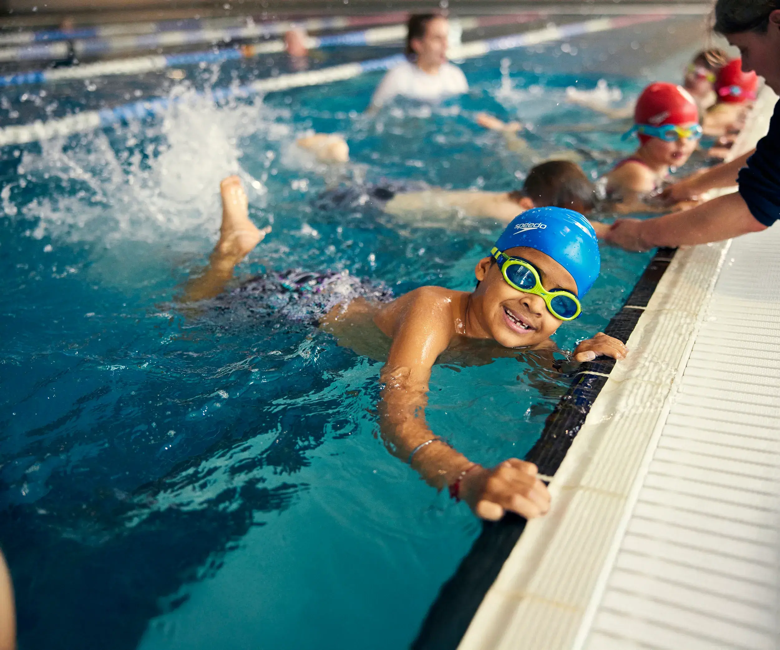 A group of children kicking while holding onto the side of the pool