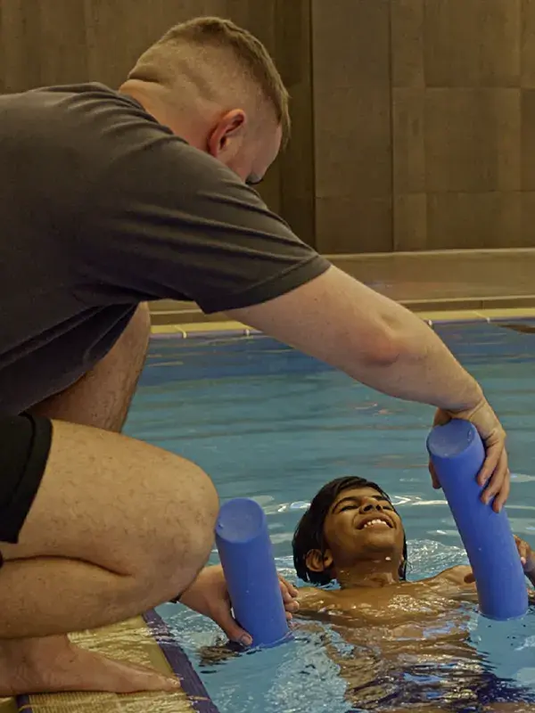 A swimming coach working with a young pool in the pool