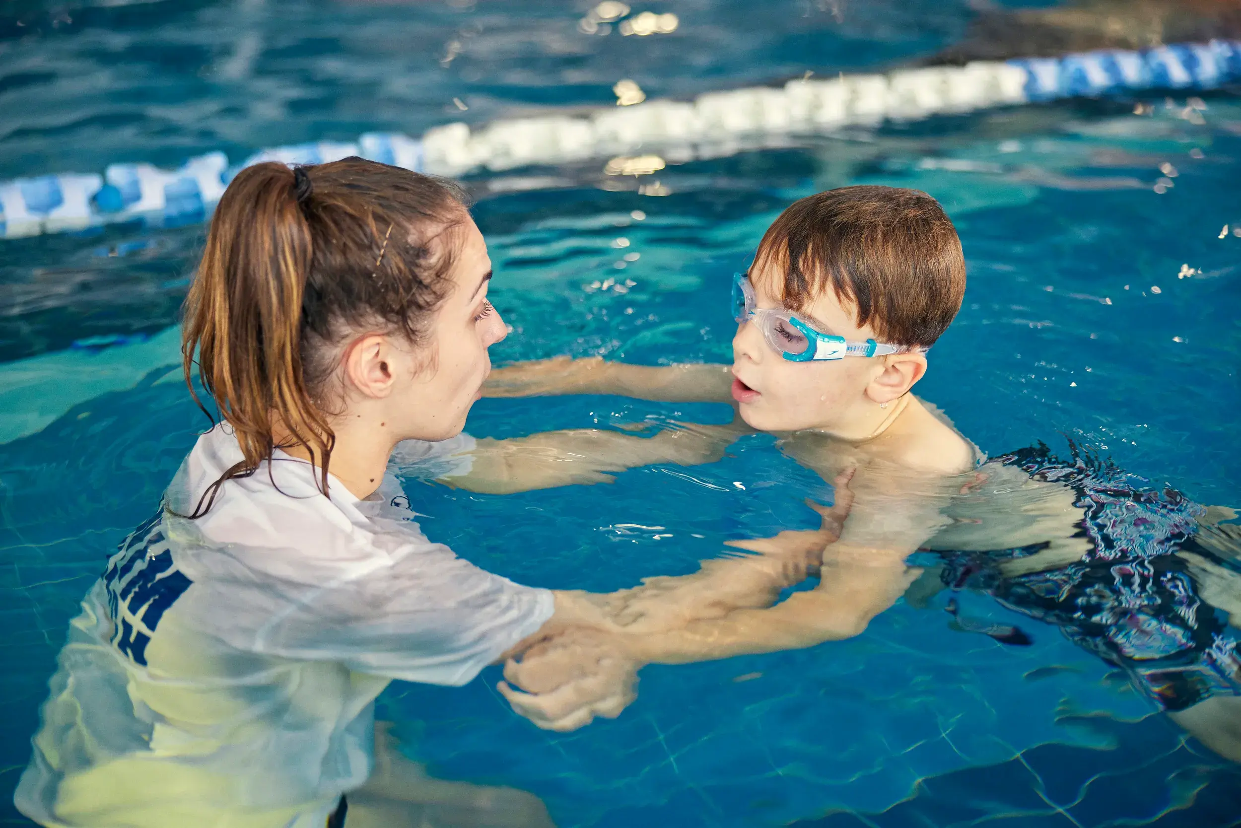 A young boy swimming with the aid of a DL swim coach