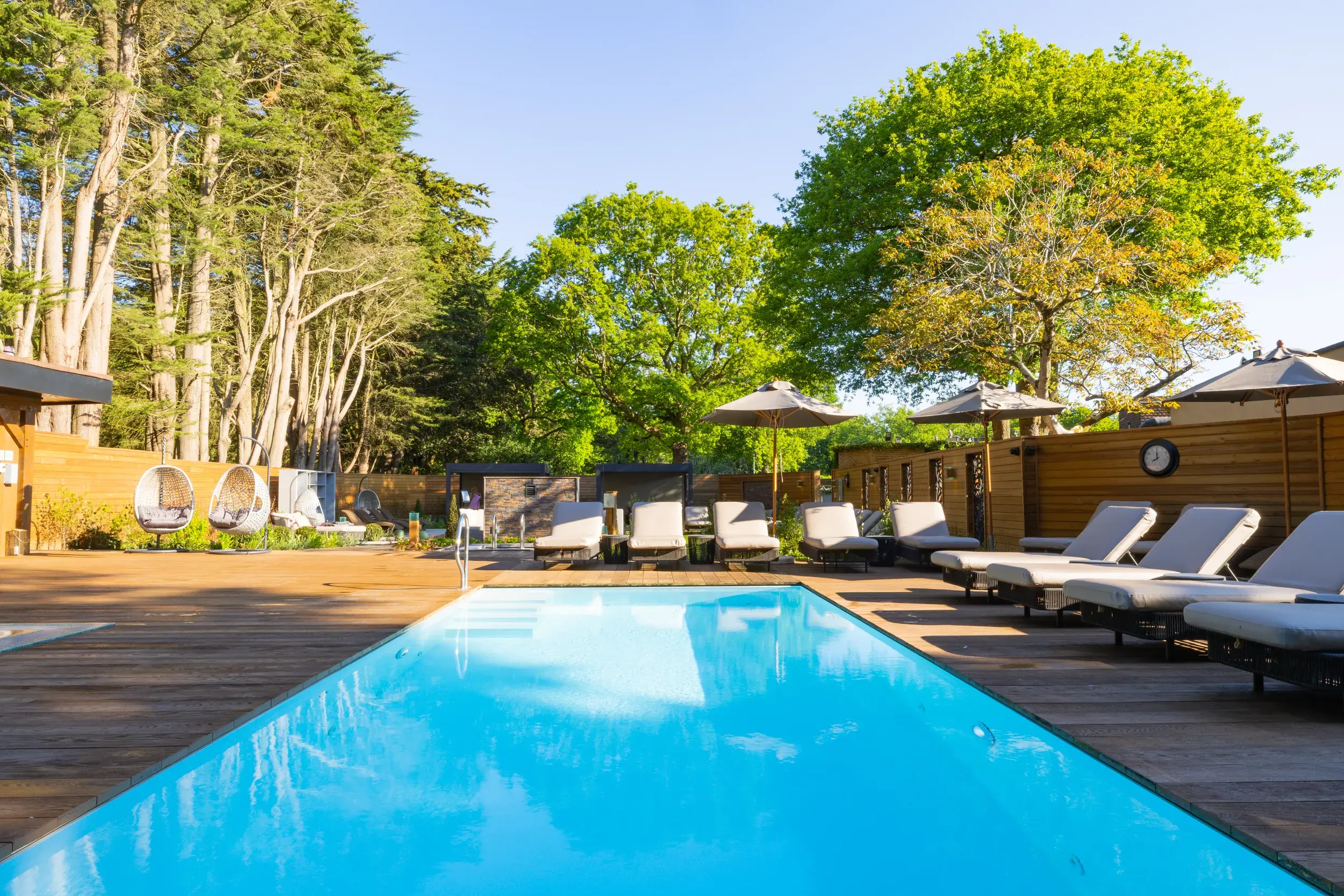 The outdoor pool at Wickwoods, a bright blue pool with loungers surrounding it