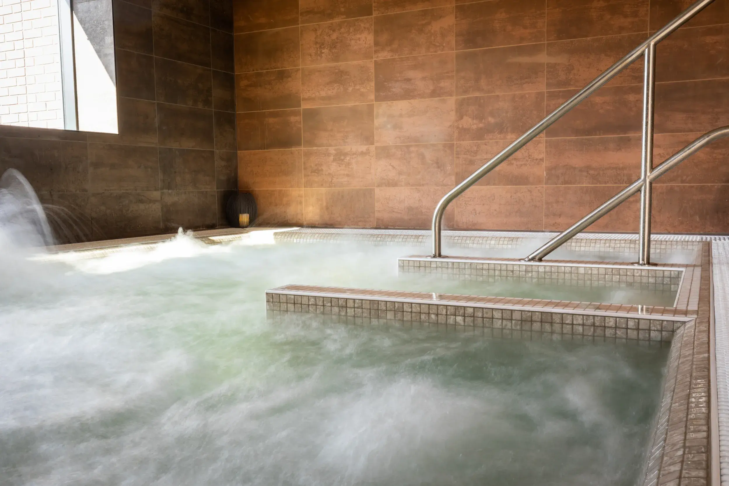 A woman reclines blissfully in a spa pool overlooking a sunny afternoon