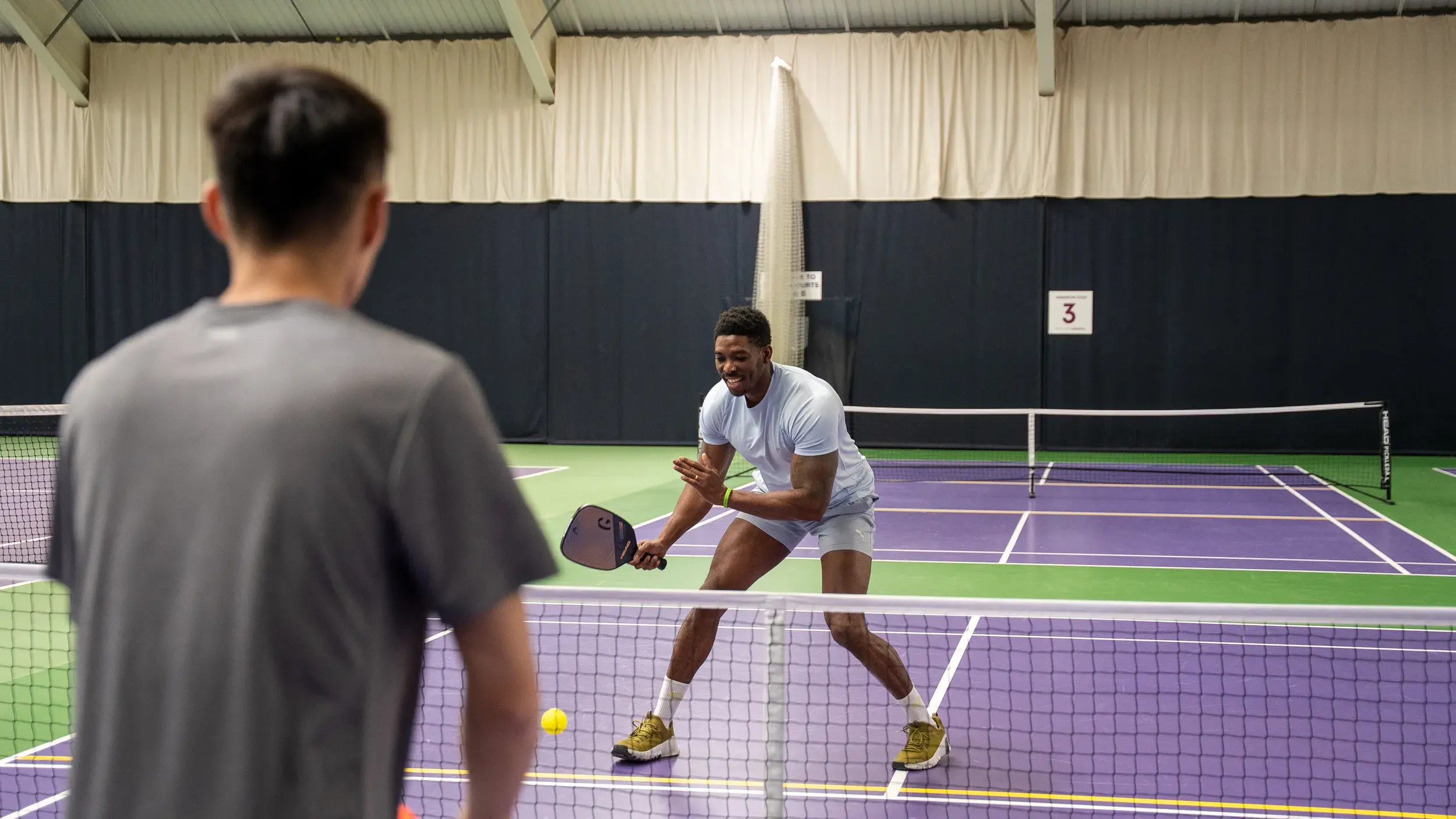 Two men playing Pickleball on an indoor court