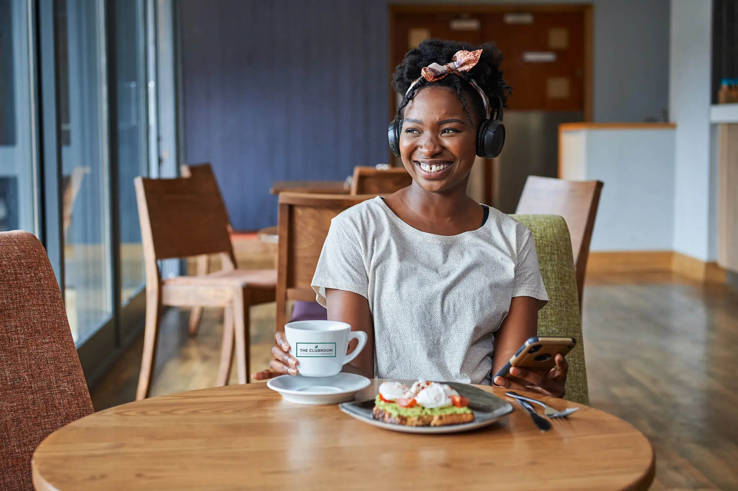 A woman smiling with a cup of coffee in front of her