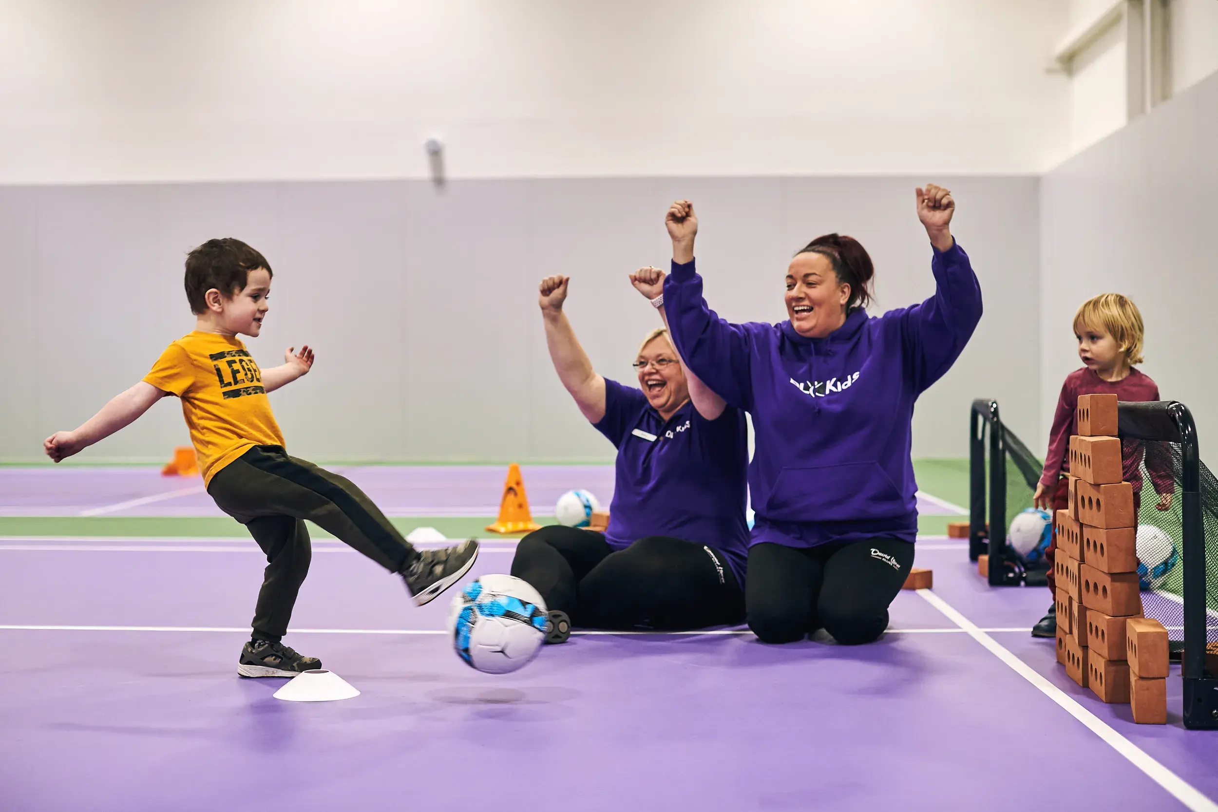 DL Kids team members cheer as a young boy scores a goal