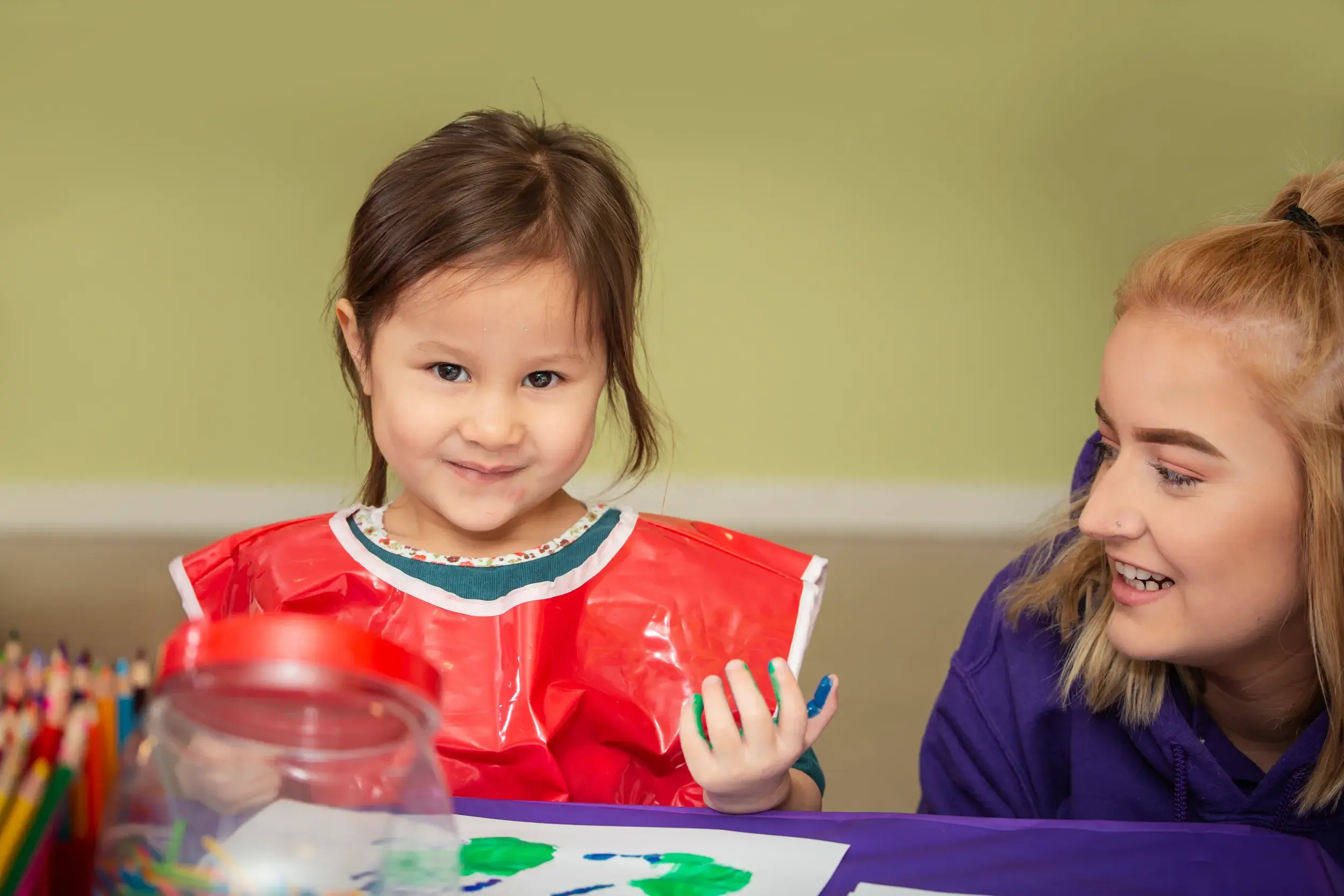 A child doing hand-painting with a member of the DL Kids team