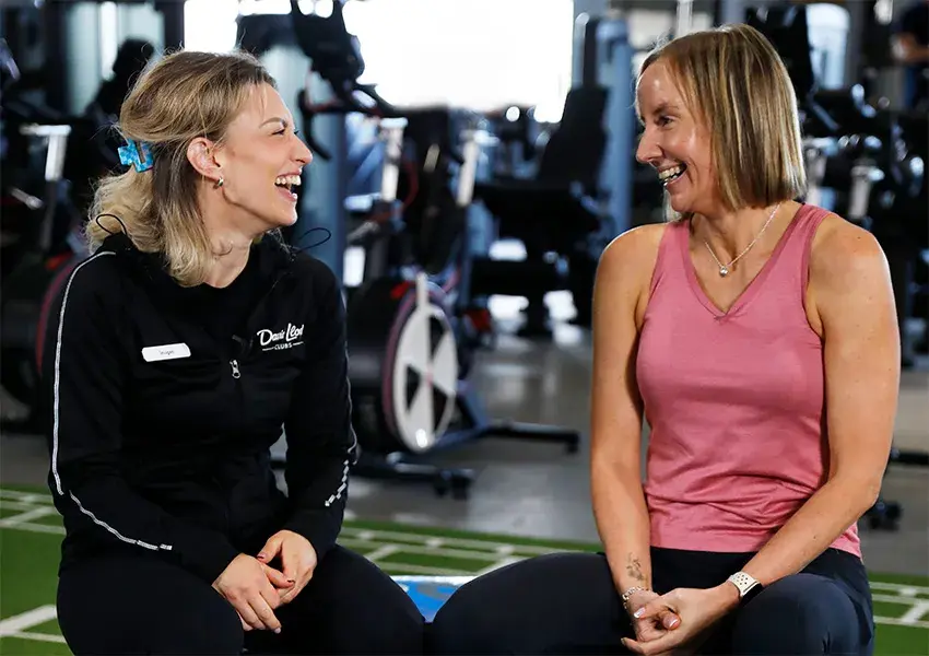 A woman sat with her personal trainer in the gym