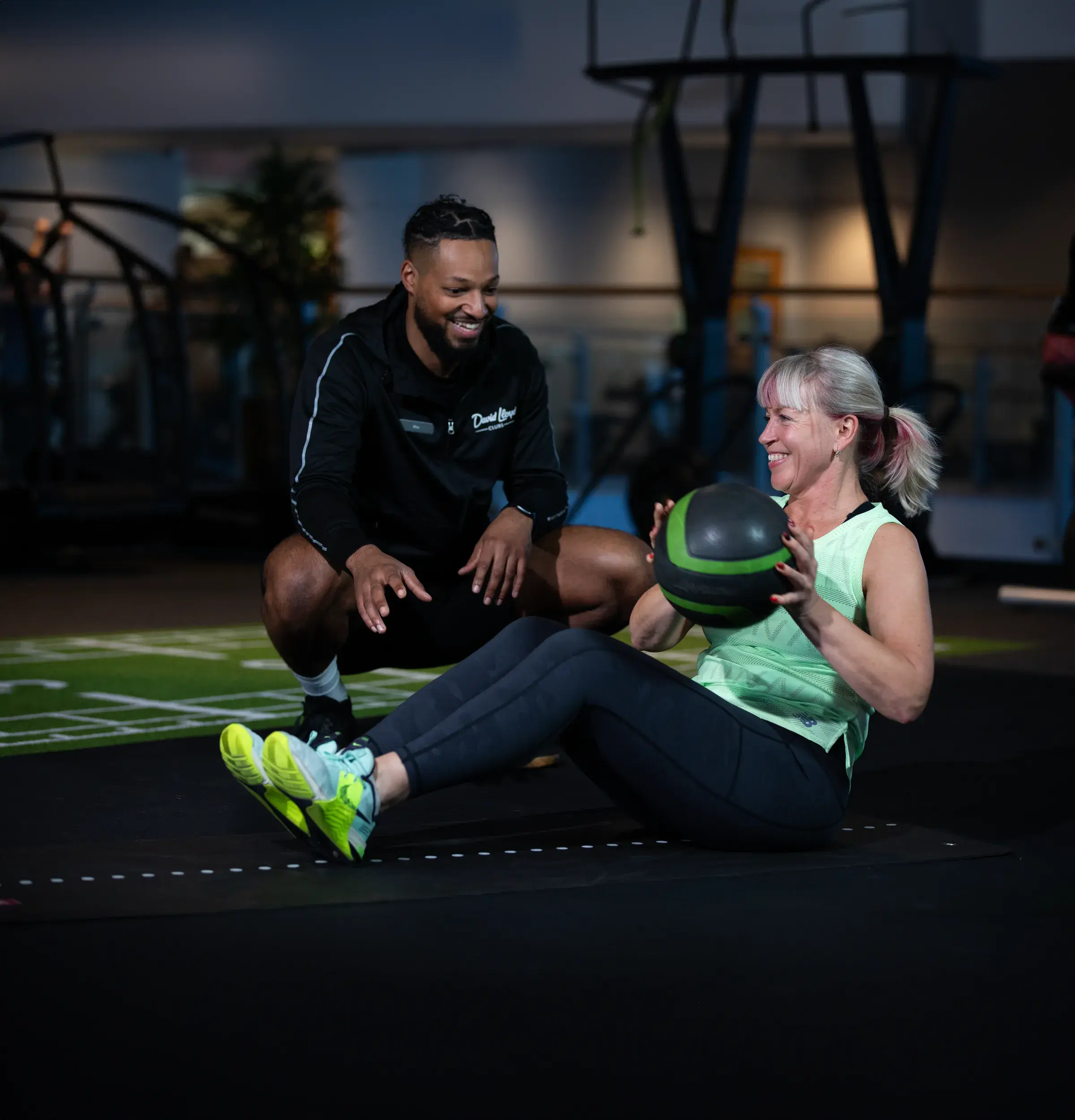 A woman exercising in the gym with her pt encouraging her