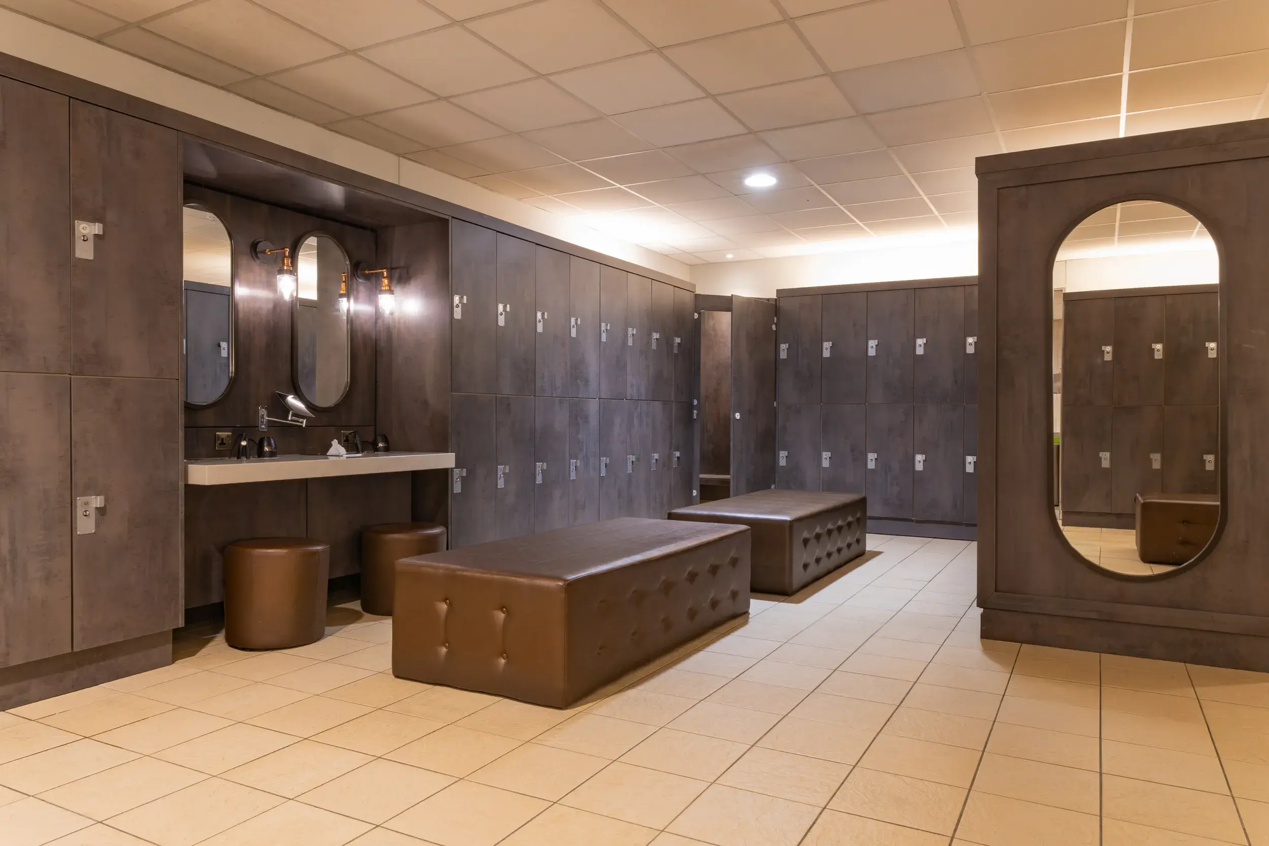 Changing room with lockers and stools to sit in front of a mirror with hairdryers