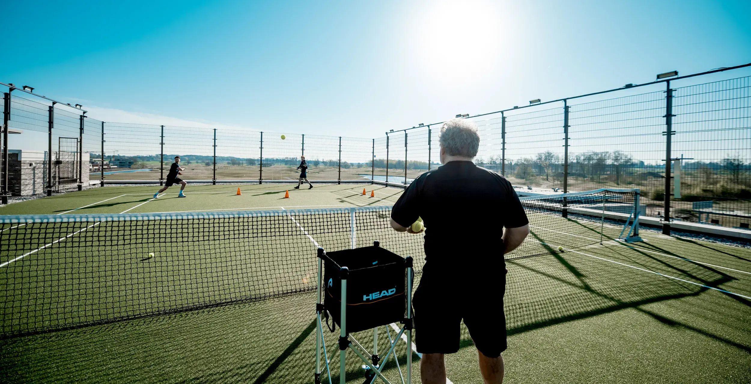 A coach teaching tennis to two adult men
