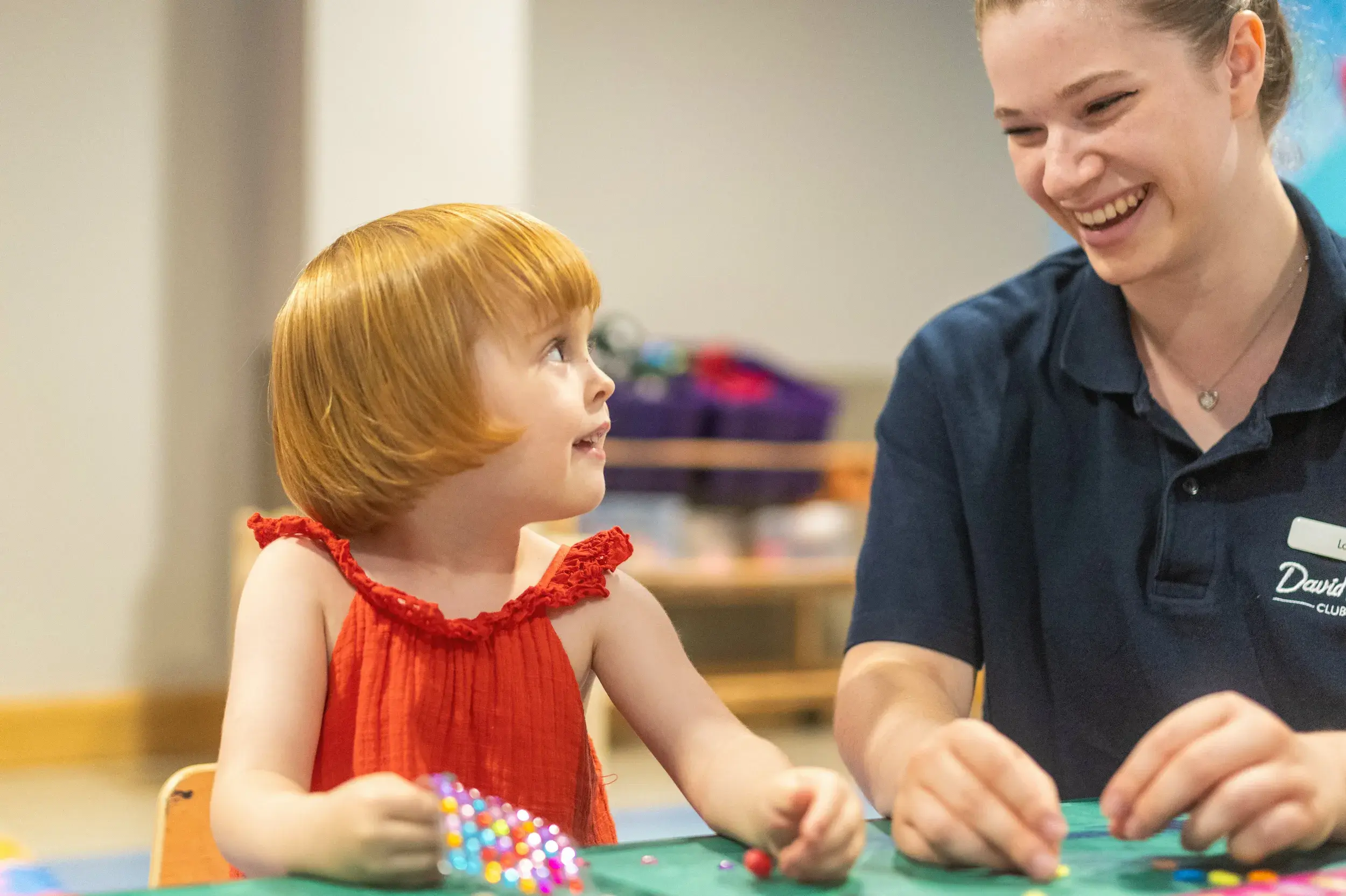A young girl holding some stickers with a DL Kids team member
