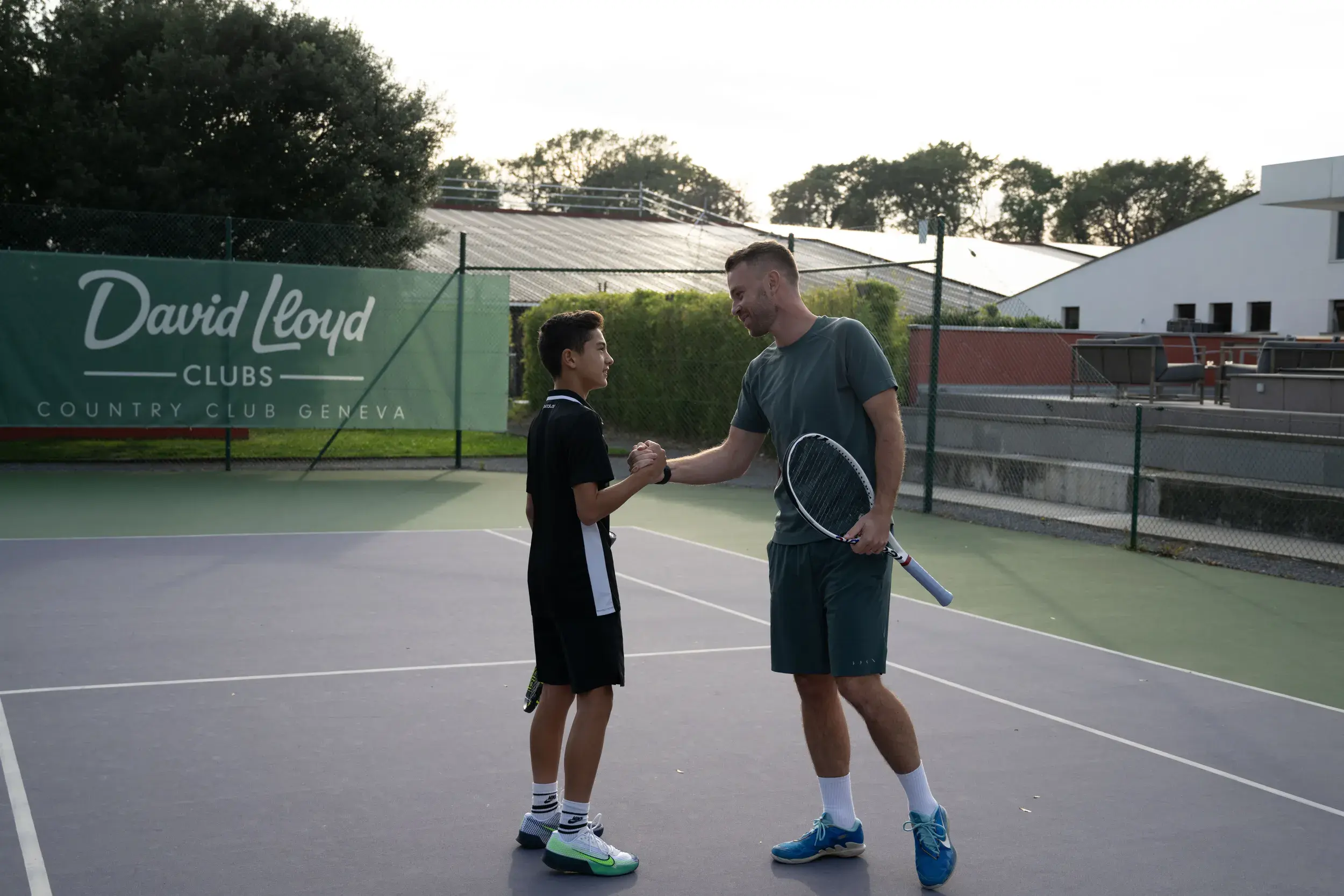 A father and son high five on an outdoor tennis court