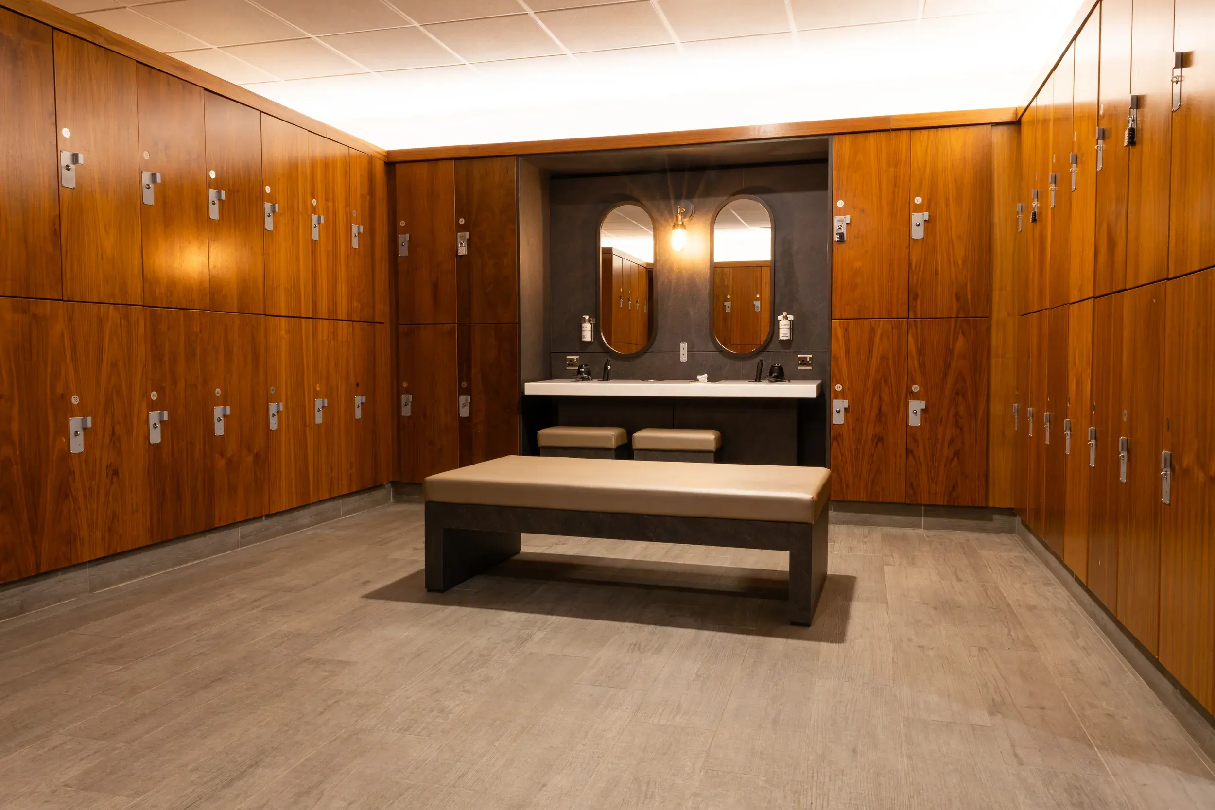 A bench in front of a mirror, surrounded by lockers in a changing room
