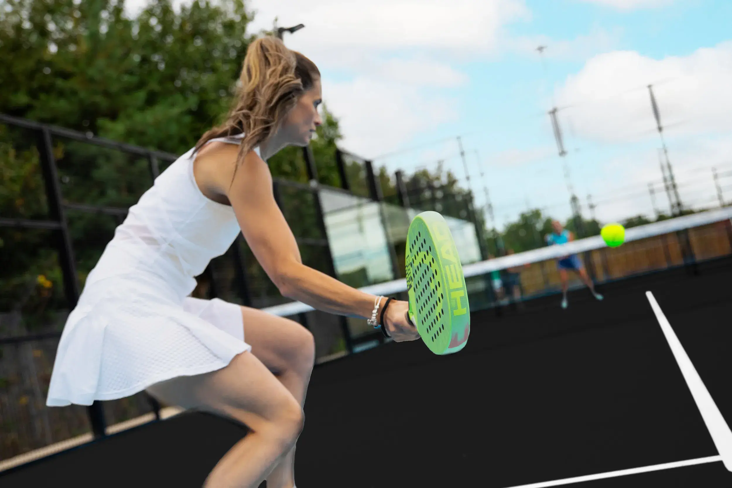 A lady swinging the padel bat in a game of Padel