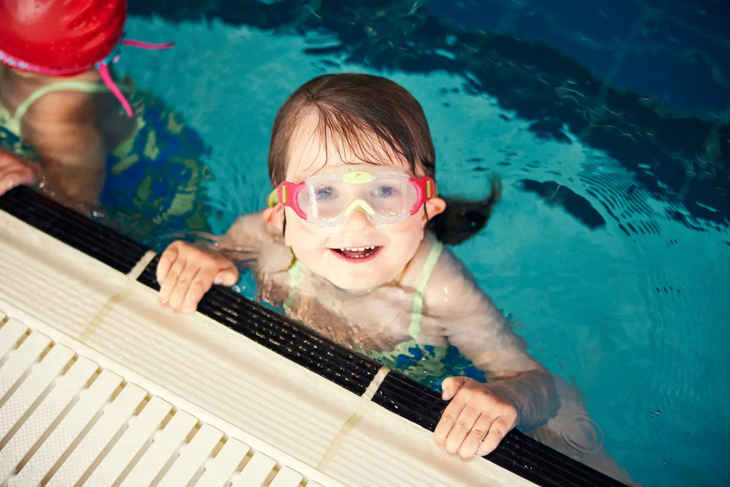 A little girl in the pool smiling 
