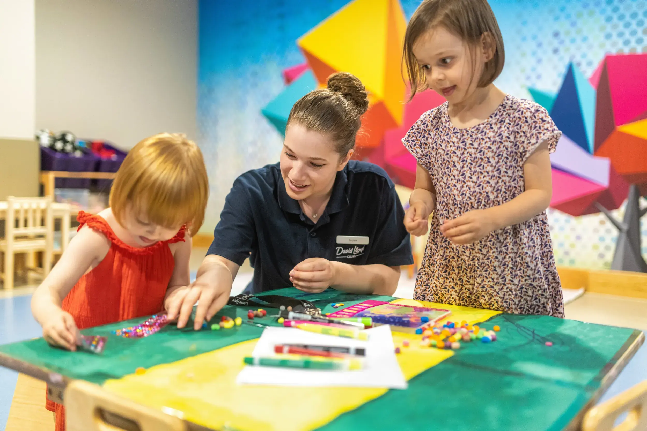 Children doing colouring with a DL Kids team member