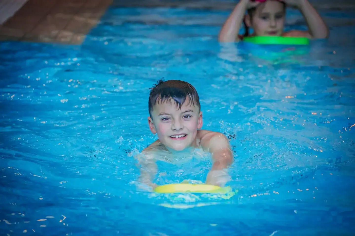A young boy swimming with a float