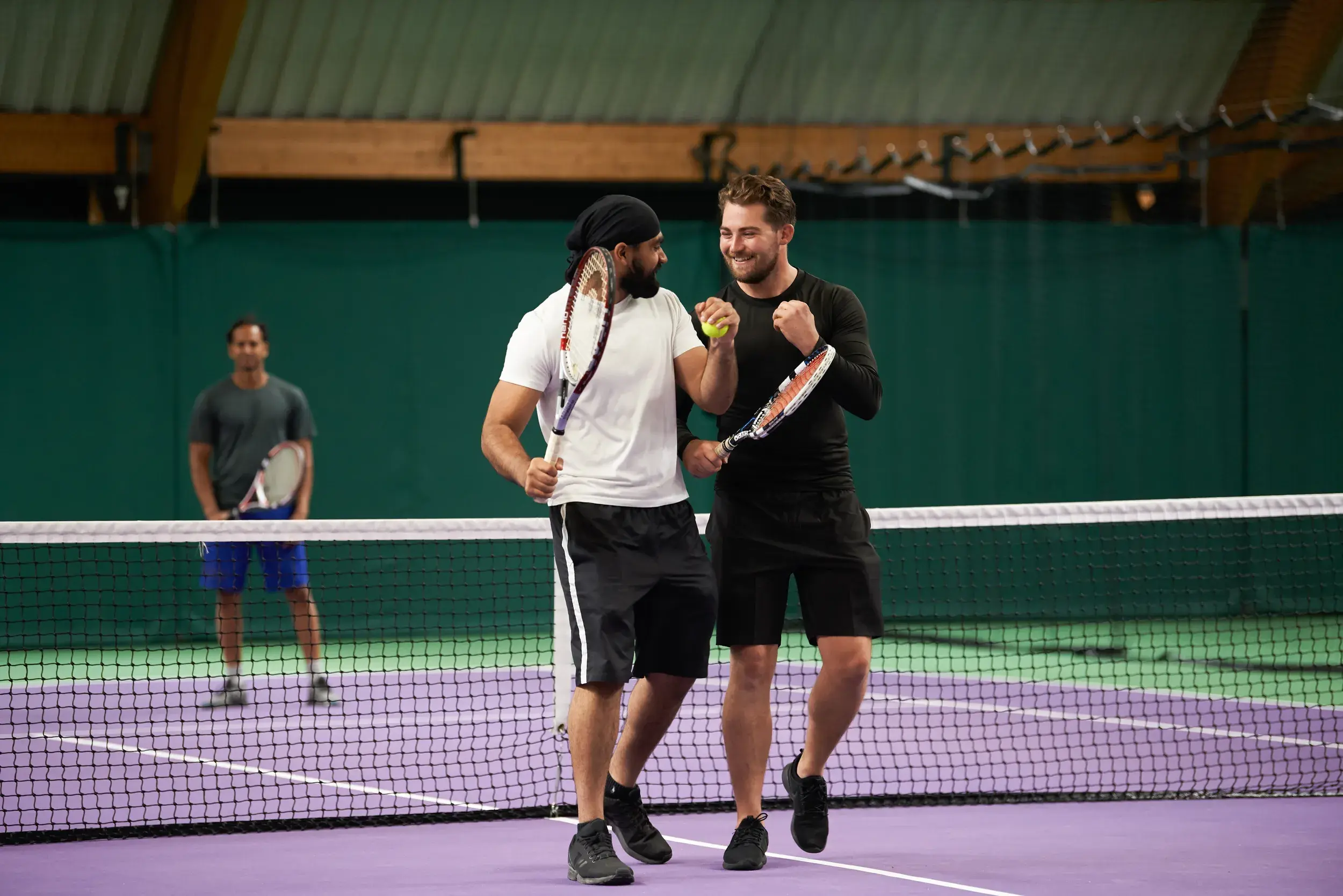 Two men playing tennis on an indoor court
