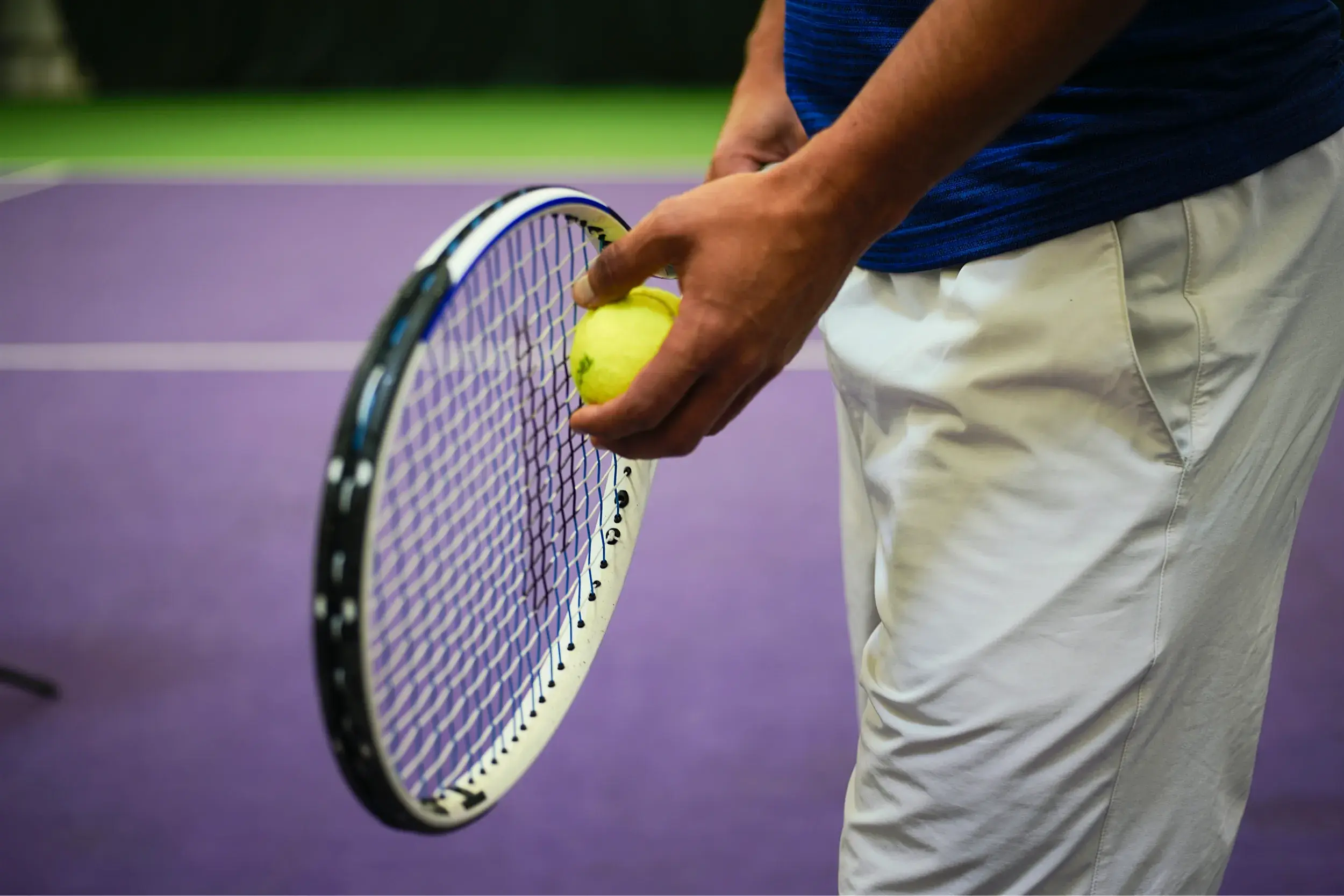 A row of tennis racquets up against a net