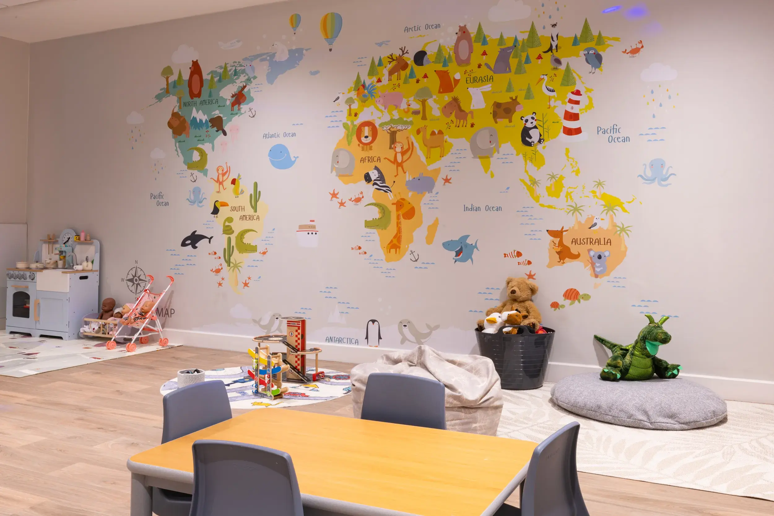 The creche with a world map on the wall, table and beanbags on the floor