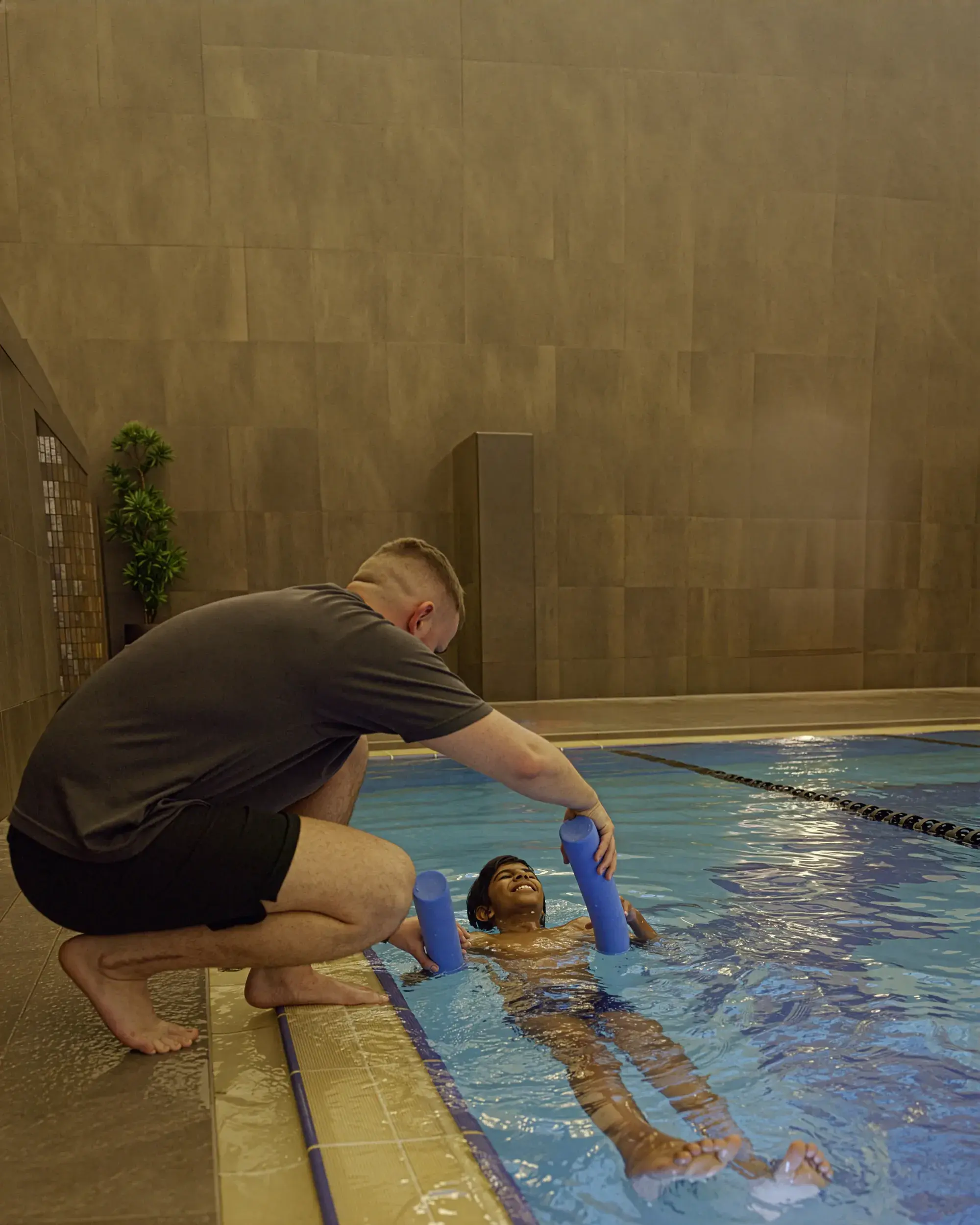A swimming coach working with a young pool in the pool
