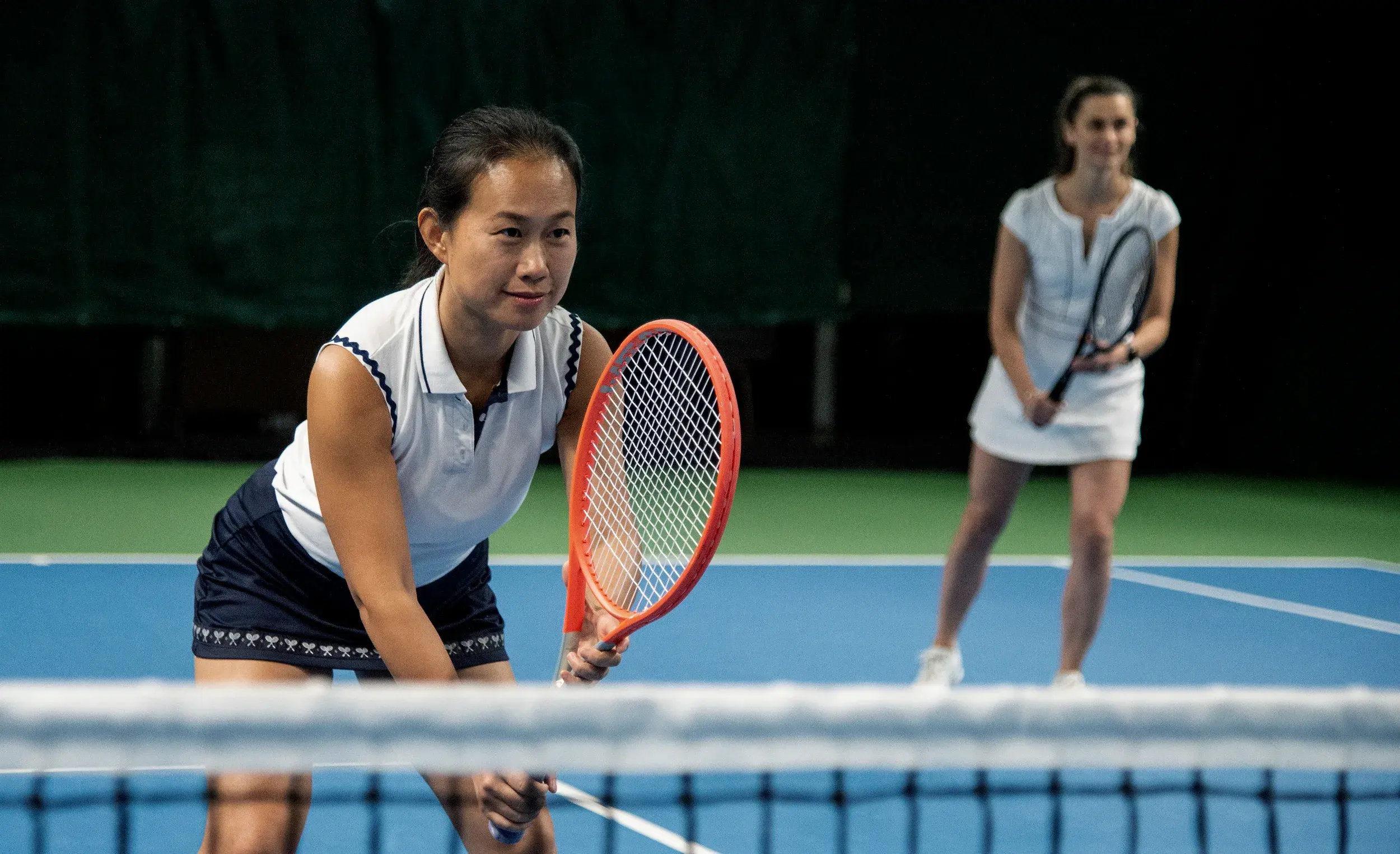 A tennis coach helps a member improve her technique
