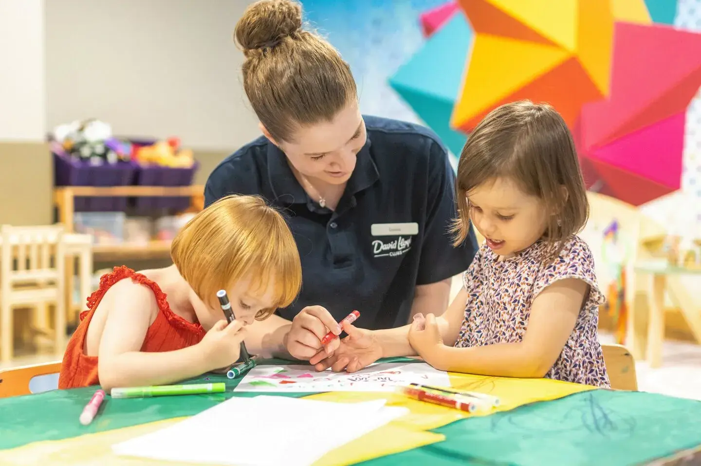 A DL Kids team member playing with two children