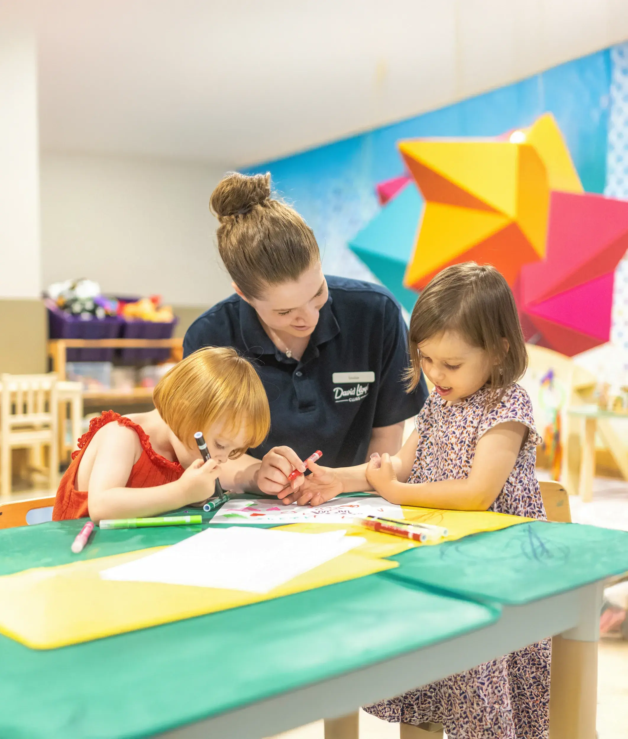 A DL Kids team member doing some crafts with two young children