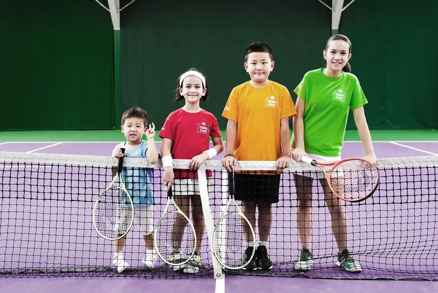 Children jumping holding tennis racquets